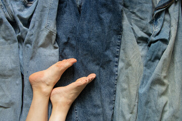 Bare feet of a young girl on the background of blue jeans, top view. The concept of fashion,...