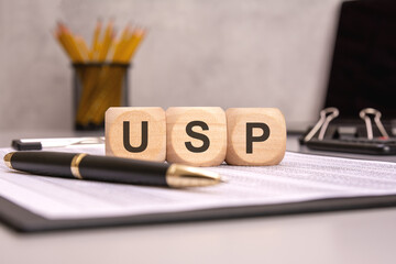 Wooden blocks with USP text on business document with pen and office items