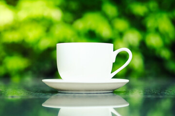 Coffee cup on the table and green nature background