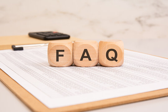 Wooden blocks with FAQ on a financial document. Frequently Asked Questions concept.