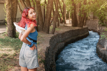 young woman walking along the river on a health trail in Almaty, Kazakhstan, enjoying sunny weather