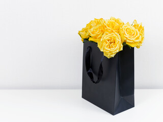 Black Gift Bag with Yellow Roses on Light Background