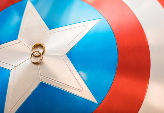 Two Gold wedding bands on a captain America shield 