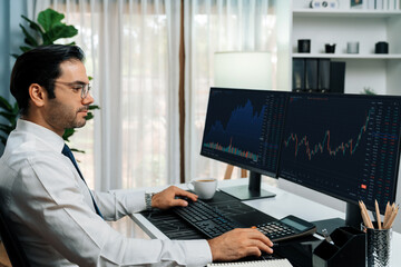 Trader businessman concentrating with two stock exchange investment to compare data analysis to...