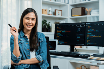 Young Asian in IT developer looking at camera to present with online information on pc with coding...