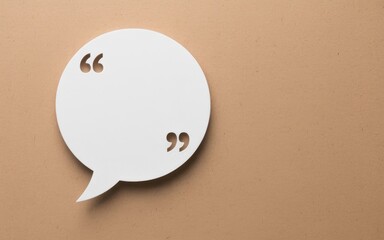White speech bubble with quotation marks on a light brown background, representing communication and ideas.