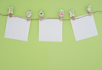 A set of white paper cards attached to a string with wooden avocado-shaped clips. The scene is...