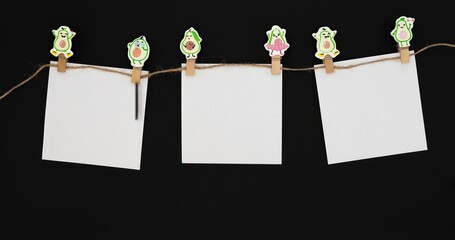 A set of white paper cards attached to a string with wooden avocado-shaped clips. The scene is...