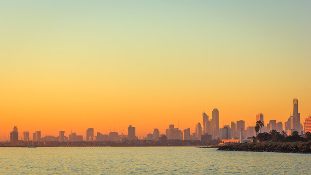 View into land across Port Phillip Bay of the City skyline at sunset, Melbourne, Victoria, Australia