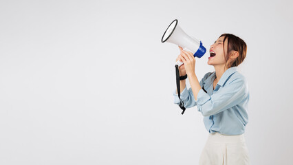 An excited woman is shouting news into a megaphone on side, making clear announcement. Her mouth is...