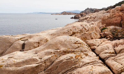 Rugged coastline of Caprera island, Sardinia, Italy. Rocky coastal cliffs and calm Mediterranean Sea under a clear sky.