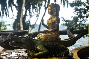 A goddess sitting on a crocodile , statue is made up of metal.