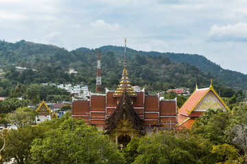 Traditional Thai temple Wat Chalong complex surrounded by green trees and distant hills under