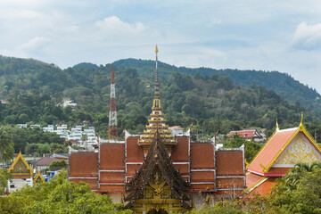Traditional Thai temple Wat Chalong complex surrounded by green trees and distant hills under