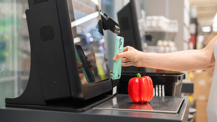 A woman buys bell peppers at a self-checkout. 
