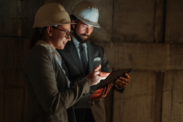 Construction managers using tablet on building site at night