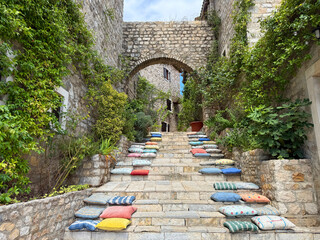 Montenegro Ulcinj stairs with colorful pillows and stone arch.