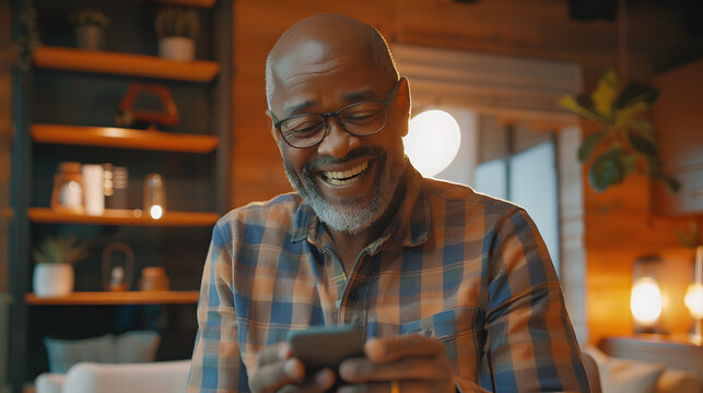 A cheerful senior African American man relaxing at home while using a smartphone.
