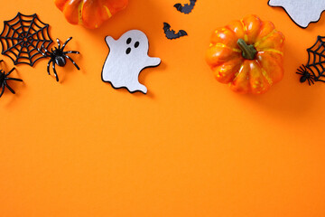 Halloween flat lay with pumpkins, bats, spiders, webs, and a ghost cutout arranged in a balanced...