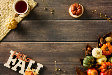 Autumn flat lay with a cozy cup of tea, yellow pumpkin, wooden bowl filled with pine cones and...