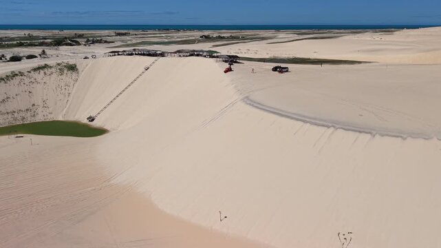 A red dune buggy is speeding down a sandy dune on Canoa Quebrada beach.