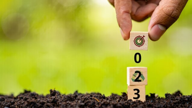 Hand Placing Wooden Blocks with Target and Numbers 0, 2, 3 on Soil, Representing Goals and Vision