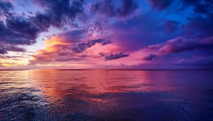 vibrant sunset sky with pink and purple clouds reflecting on ocean surface at dusk