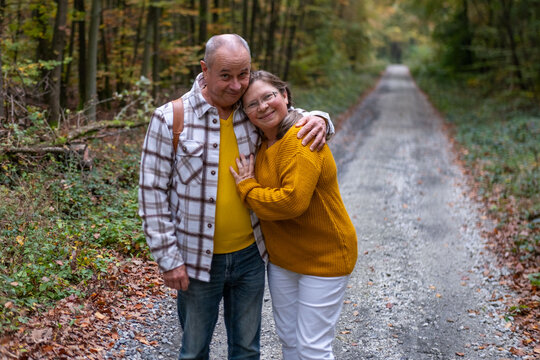 Happy Active mature couple walking through autumn forest trail together showing love and unity, happiness forest trail, golden years, outdoor activity, scenic route