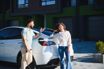 Couple charging electric car at home, embracing sustainable transportation