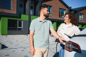 Happy couple charging electric car at home, embracing green energy and sustainable lifestyle