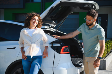 Couple charging electric car at home, embracing green energy and sustainable lifestyle