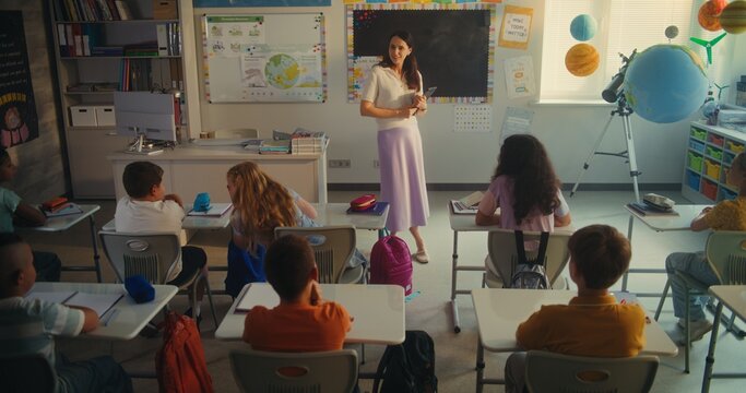 Environmental Science Lesson: Female Teacher with Tablet Computer Educating Smart Diverse Kids. Primary School Children Studying Renewable Energy and Solar System in Modern Classroom. STEM Education.