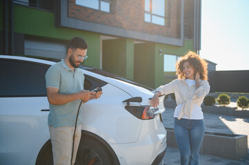 Couple charging electric car at home using green energy