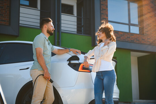 Couple charging electric car at home, embracing green energy and sustainable lifestyle - Powered by Adobe