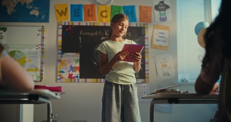 Smart Primary School Girl with Notebook Showcasing Knowledge of Ecology in Front of Class and...