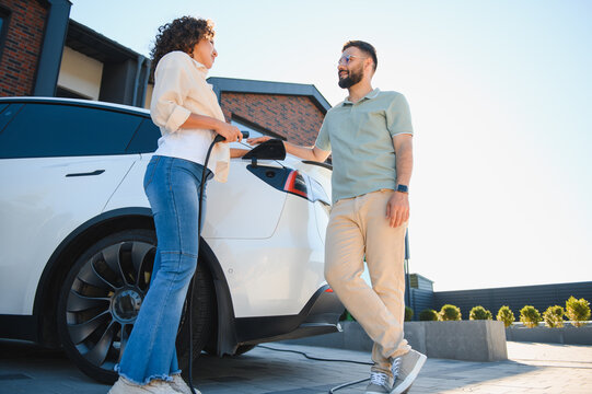Couple charging electric car at home, embracing green energy and sustainability - Powered by Adobe