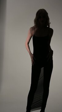 Fashion photo of young beautiful woman in black dress posing in studio