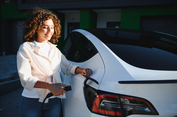 Young woman charging electric car at home