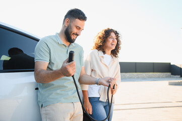 Happy couple charging electric car at home, embracing green energy and sustainable lifestyle