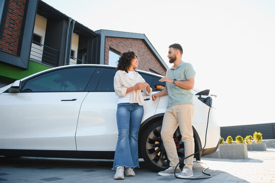 Couple charging electric car at home, embracing green energy and sustainable living