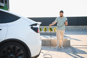 Man Charging Electric Car at Modern Charging Station