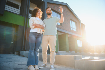 Happy couple showing keys of their new modern house