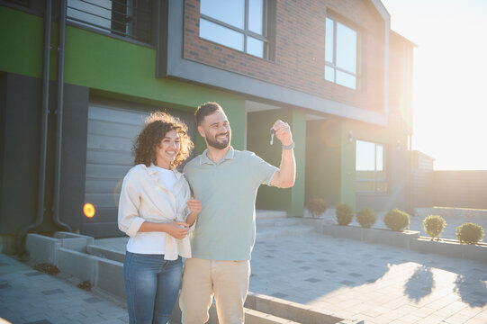Happy couple showing keys of new house, celebrating real estate purchase