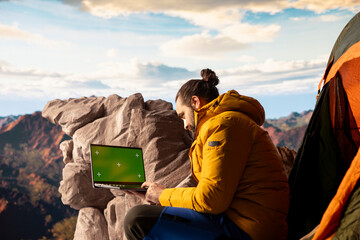 Adventure seeker stands at a mountain peak next to isolated chroma key, looking out at the scenic...