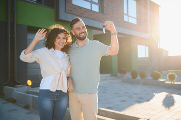 Happy couple showing keys to their new house, celebrating buying real estate property