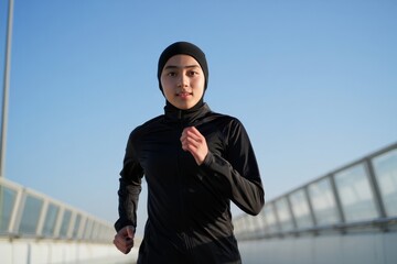 Muslim Woman Running on Bridge - Active Lifestyle and Fitness