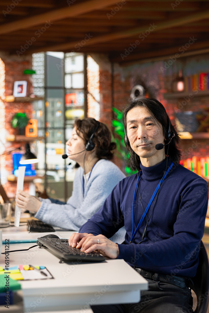 Poster portrait of senior call center agent typing on pc keyboard, assisting customers through digital comm