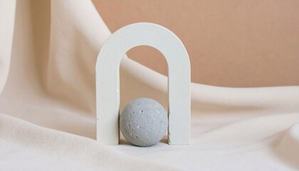 Abstract plaster form (arch, sphere, shapeless figure) on an ivory or cocoa-colored background. Object stands on fabric or polished stone. Minimalism with an artistic touch.