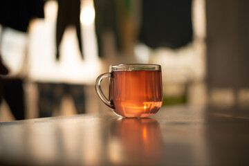 A transparent glass with tea, juice, lemonade, on a smooth glossy table. Dark evening photo creative. Side view. High quality photo