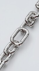 Obraz premium Close-up of a shiny silver metal chain showcasing the intricate links and texture in a minimalist setting